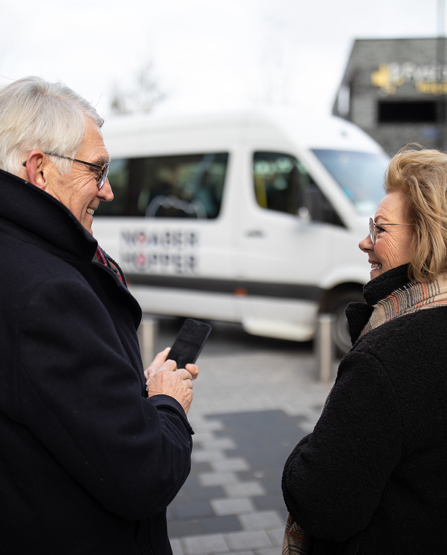 Man en vrouw voor Noaberhopper busje die een rit boeken.